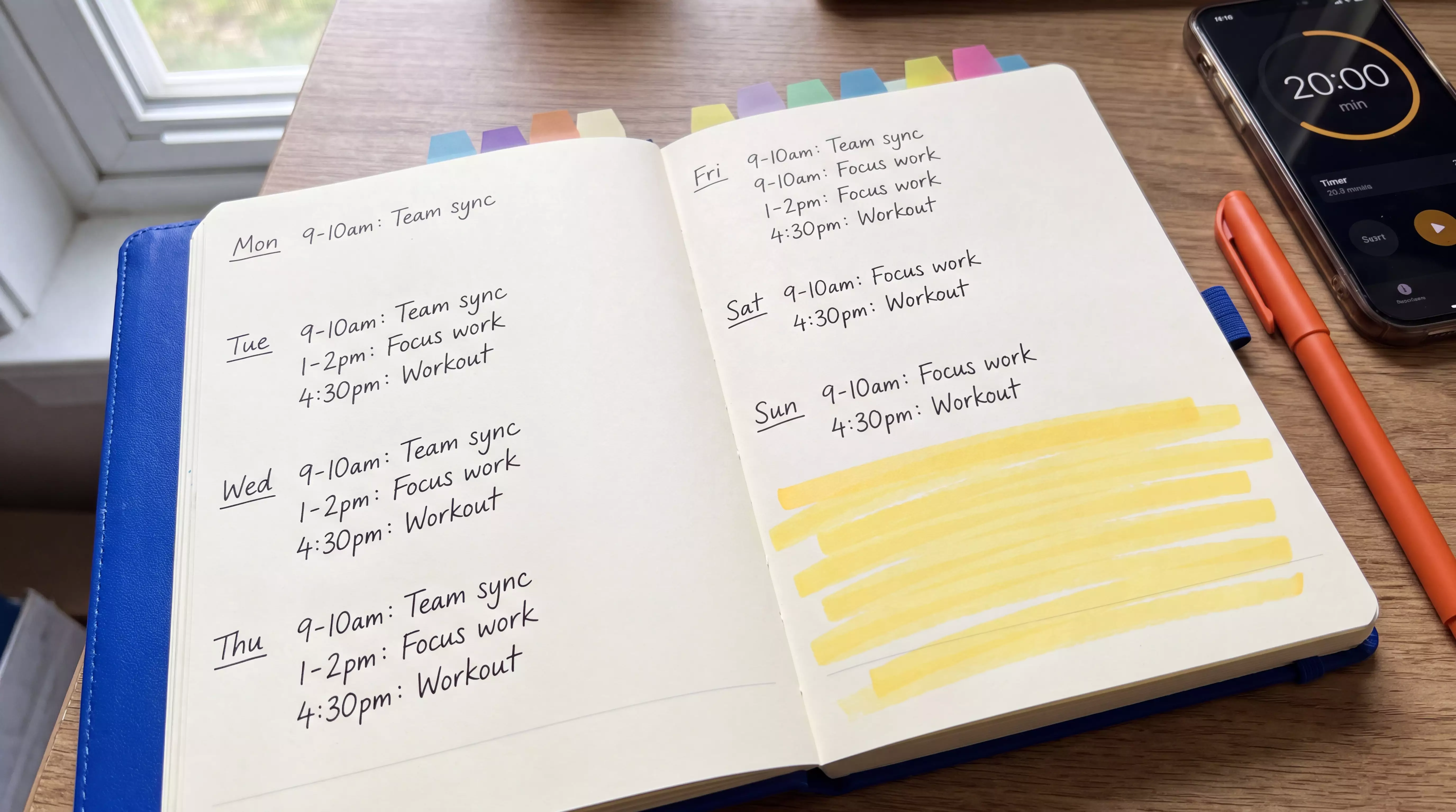 Planner with time blocks beside a phone